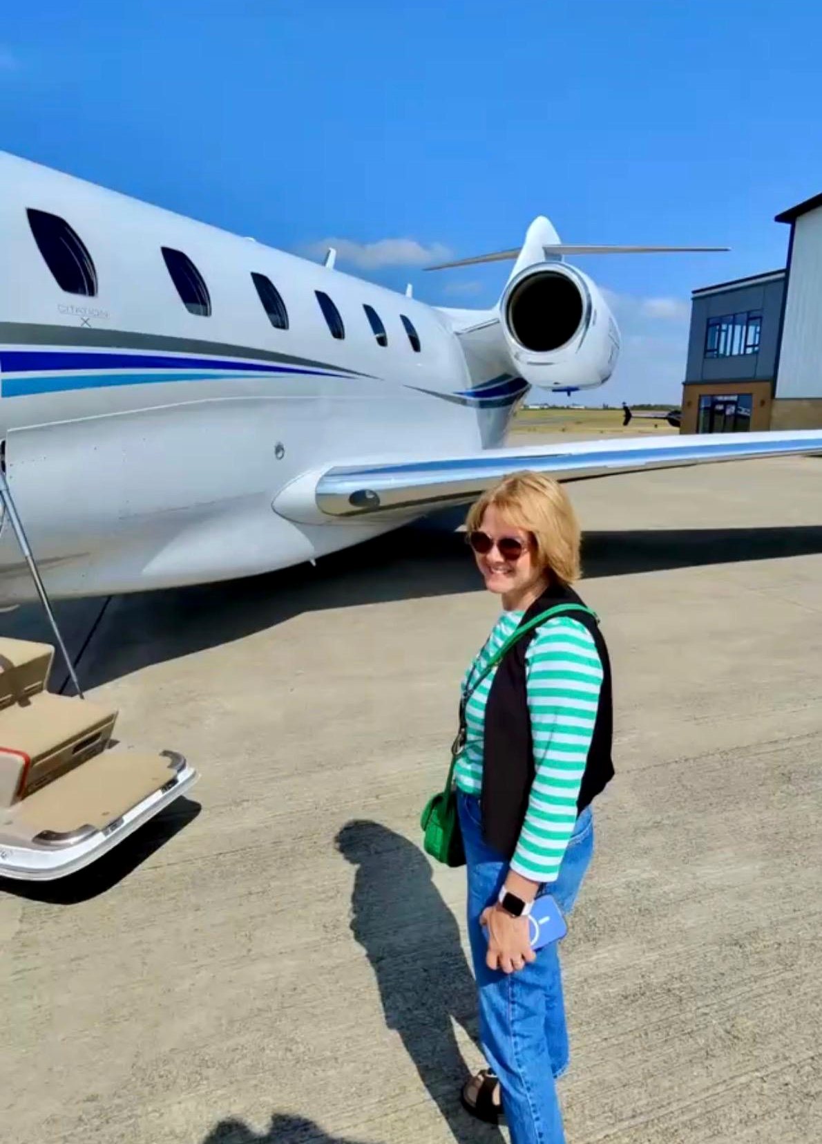 A passenger on the apron beside the Citation X with the airstair down on a clear day