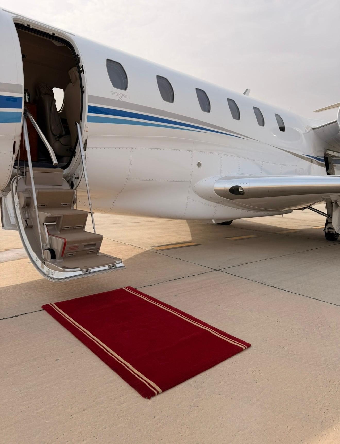Airstair of the Citation X lowered with a red carpet laid at the foot of the steps